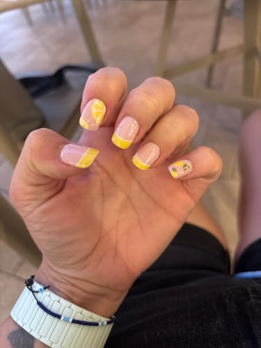 Customer's hand showing UV Gel Lemon Sorbet nail wraps featuring yellow lemon designs and French tips on short nails.