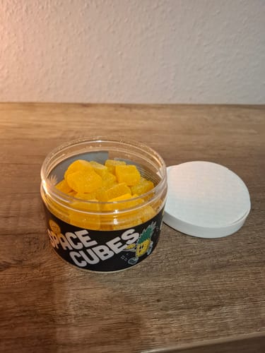 Kundenfoto der offenen Dose THC Space Cubes, gefüllt mit gelben, würfelförmigen Gummibonbons.