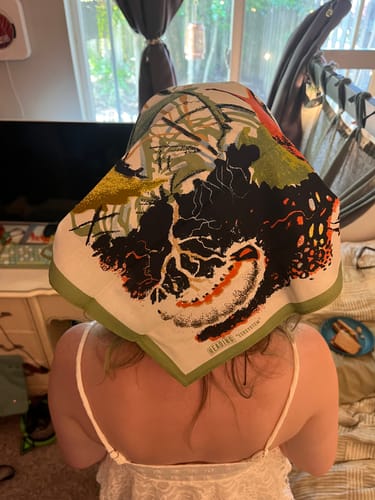 Customer's Ecosystem Bandana with colorful, detailed forest nature illustrations draped over their head.