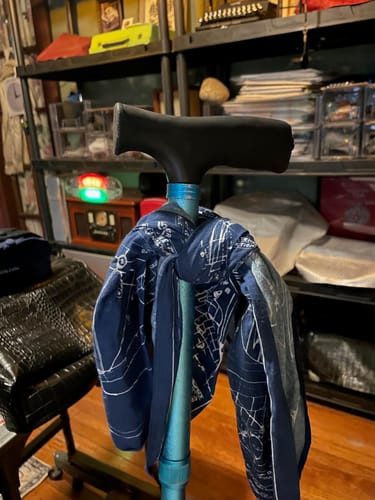 Customer's blue Flight Bandana with white blueprint designs tied around the handle of a blue cane.