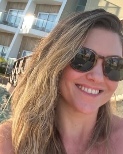 Customer's Óculos de Sol Jurerê com armação escura e lentes verdes, sendo usado por uma pessoa em um ambiente externo.