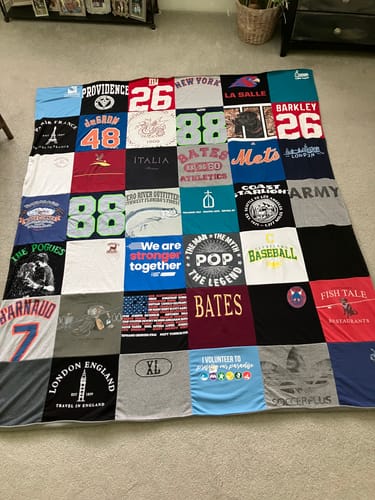 Customer's Project Repat T-Shirt Quilt featuring various colorful vintage t-shirt patches laid out on a carpet.
