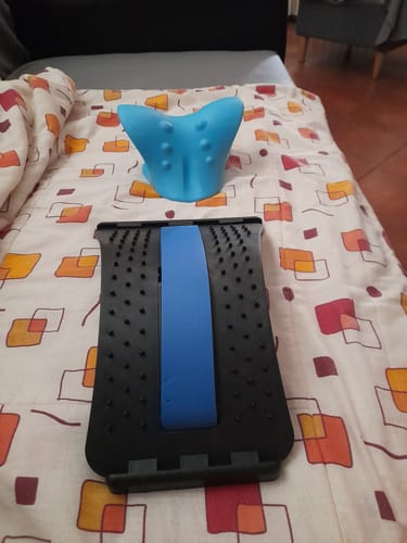 Vásárló fekete és kék tartásjavító hátnyújtója és egy kék nyaktámasz egy ágyon.