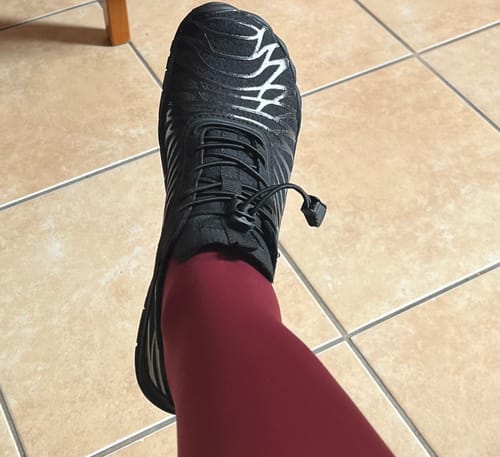 Vásárló lábán a fekete Flexies Barefoot cipő, ezüst mintával az orrán.