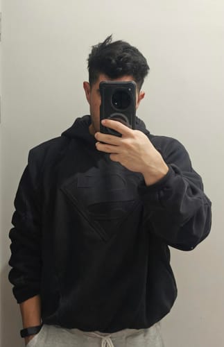 Reviewer wearing the black Superman Shield Hoodie, showing the tonal embossed logo on the chest.