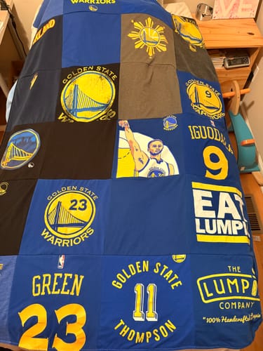 Customer's Project Repat T-Shirt Quilt made from Golden State Warriors basketball shirts, spread out on a bed.