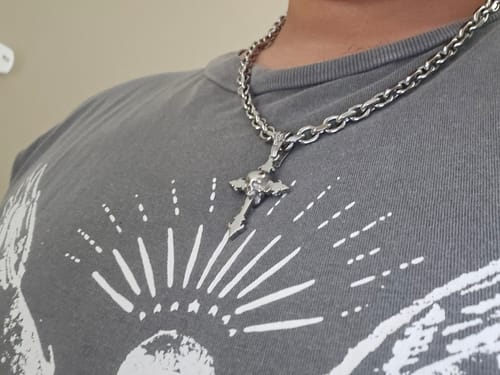Close-up of a reviewer wearing the silver Down Your Throat Pendant on a thick chain against a grey shirt.