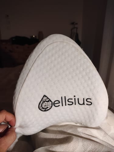 Gros plan du coussin orthopédique blanc Cellsius pour genoux, tenu par un client.