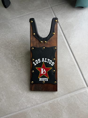 Customer's black leather and wood boot jack with gold studs, viewed from the top on a tile floor.