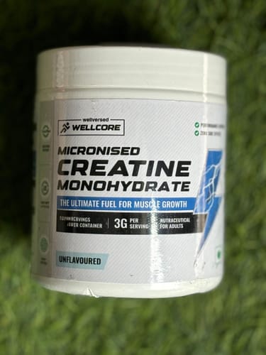 Customer's white tub of Wellcore Micronised Creatine Monohydrate, showing the unflavoured front label on a green surface.