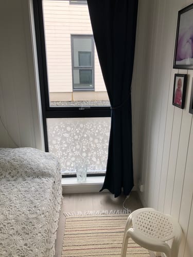 Anmelder viser Static Tord vindusfolie på et vindu i et soverom, ved siden av en seng.