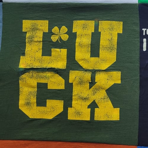 Close-up of a repaired 'LUCK' t-shirt panel on the customer's Premium T Shirt Quilt.