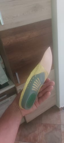 Vásárló kezében tartja a sárga és zöld Ortopéd Pro Talpbetétet.