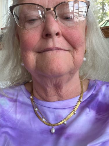Close-up of a reviewer wearing the layered Chelsea Herringbone Necklace bundle with pearl details.