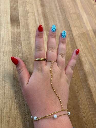 Reviewer's hand showing the gold Spins Tidal Roller Ring on their ring finger.
