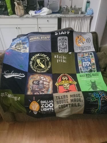 Customer's colorful Project Repat T-Shirt Quilt made from various shirts, displayed on a couch.