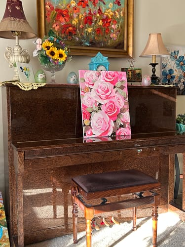 Reviewer's completed Rosy Elegance painting of pink roses sitting on a dark brown piano.