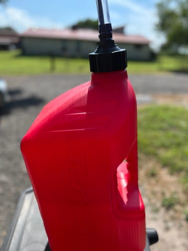 A customer's replacement Storage Cap with a spout attached to a red jug outdoors.