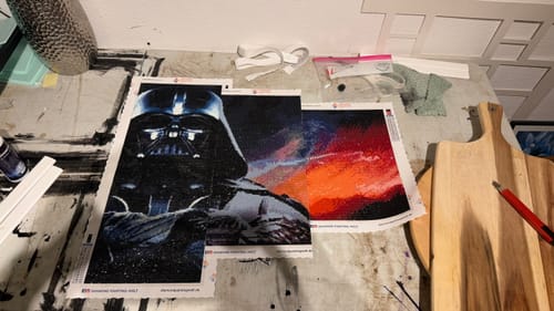 Kunde zeigt sein Diamond-Painting 'Darth Vader' auf einem Arbeitstisch.