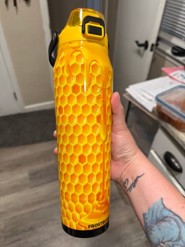 Reviewer holding their yellow Bottle Buddy with a detailed honeycomb and dripping honey design.