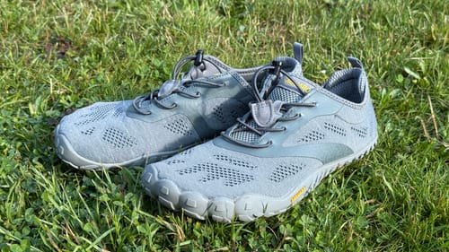 Ein Paar graue Smart Ⅰ Barfußschuhe eines Kunden, die auf einer Wiese liegen.