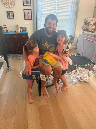 A customer with two children holding the Bottle Buddy 32oz Michigan Wolverines bottle and its packaging.