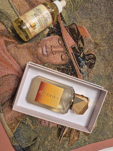 Reviewer's Vanillionaire Eau de Parfum displayed in its box next to a bottle of body drops on a patterned surface.