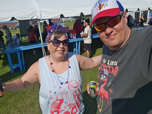 Customer smiling in her Eagle Boop Comfort Colors Tank Top at a festive outdoor 4th of July celebration.
