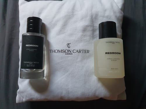 Customer's Redroom Eau de Parfum and complimentary body wash displayed on a white branded pouch.