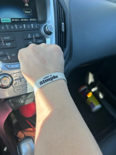Customer wearing the light-colored 'Keep it Simple' bracelet on their wrist inside a car.