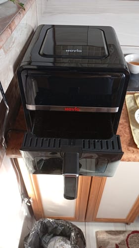 Client arătând friteuza Air Fryer Novio StonePro cu cuva neagră scoasă pentru a vedea interiorul.