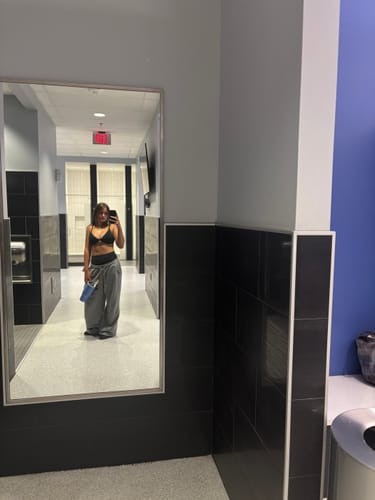 Reviewer takes a mirror selfie in a bathroom, showing the oversized fit of the grey W2296 Super Baggy Sweats.