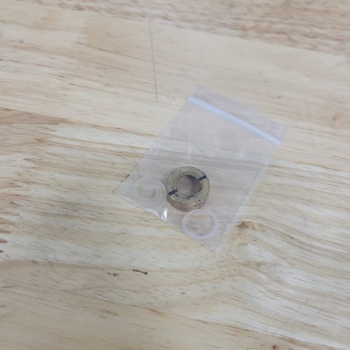 Reviewer's Atomstack Window Lens Replacement parts, showing the included locking nut and gaskets in their packaging.