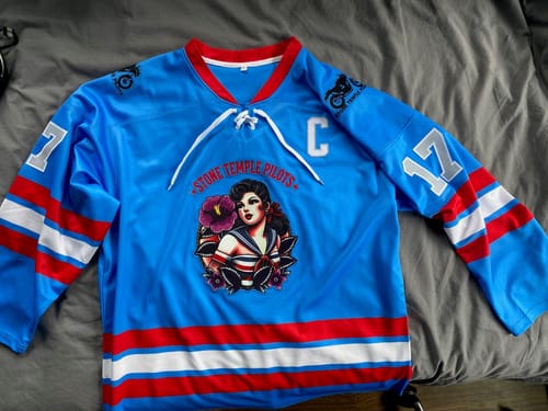 Customer's customized blue and red hockey jersey with a large front logo and striped sleeves, laid out flat.