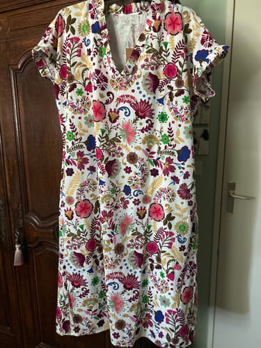 Robe Acacia d'une cliente avec son imprimé floral coloré, suspendue devant une armoire.