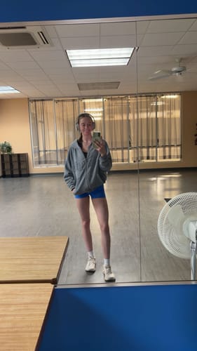 Customer wearing the oversized grey W532 After Dark Hoodie in a dance studio mirror selfie.
