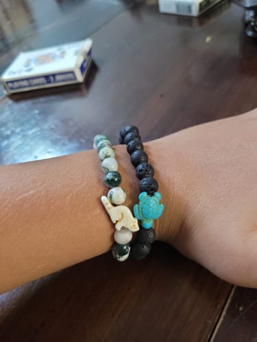 Customer's wrist showing two beaded bracelets from their collection, one with a turquoise sea turtle charm.