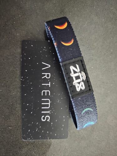 Customer's Artemis Bracelet with a colorful moon pattern next to its starry backing card.