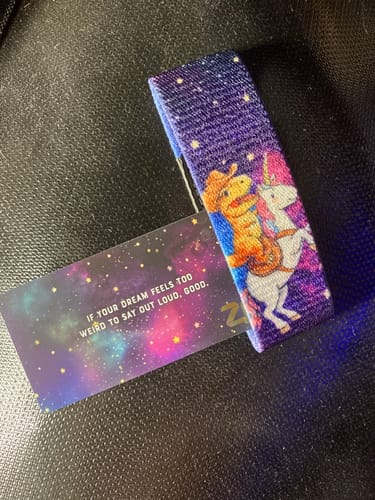 Customer's 'Giddy Up' bracelet from the Beyond The Stars Collection, showing a dinosaur on a unicorn against a starry background.