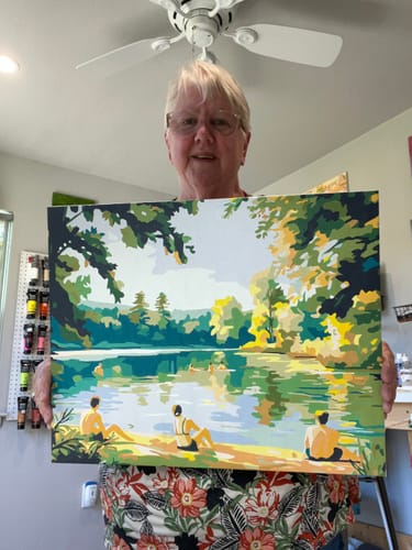 A reviewer holds up her completed, colorful 'The Bathers' paint-by-numbers canvas.