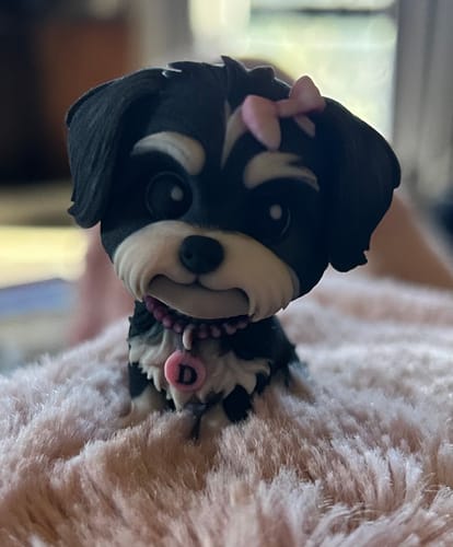 Customer's custom action figure of a small black and white dog with a pink bow and collar.