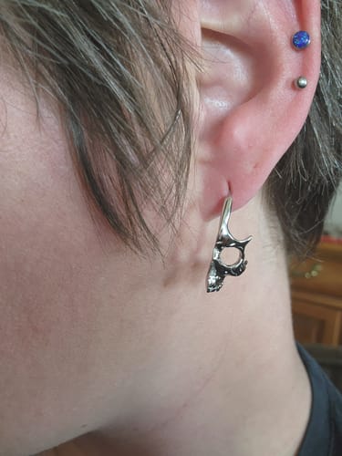 A close-up of a customer wearing the silver Skull Hoop Earring in their ear.