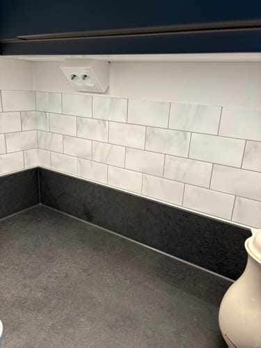 Anmelderens kjøkken med ferdig monterte Subway marmorfliser over en mørk benkeplate.