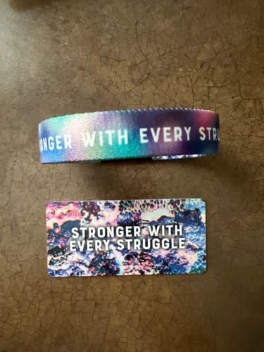 Reviewer's colorful Stronger With Every Struggle Bracelet and matching collector's card laid out on a surface.
