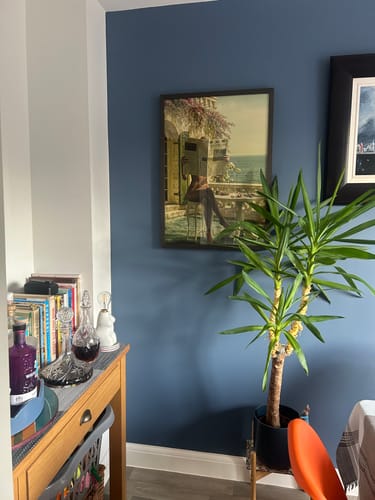 Customer's Dark Oak Gallery Frame with an art print, hung on a blue wall in their home.