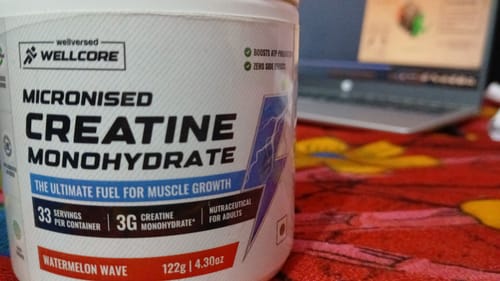 Customer's white tub of Wellcore Creatine Monohydrate in Watermelon Wave flavor on a desk.