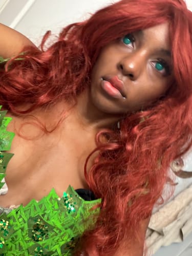Reviewer in cosplay with a red wig, showing the vibrant look of the green mesh contact lenses.