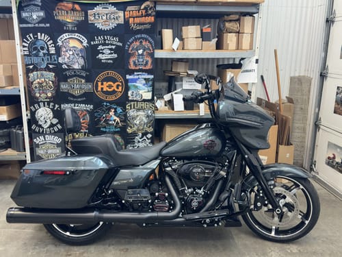 Customer's Project Repat T-Shirt Quilt made from Harley-Davidson shirts, hanging on a wall behind a motorcycle.
