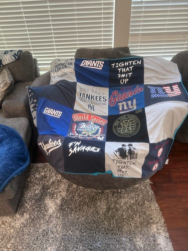 Customer's Premium T Shirt Quilt made from sports-themed shirts, including the Giants and Yankees, draped over a chair.