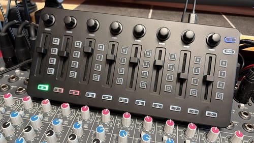 Ein Kunde zeigt den schwarzen Donner Starrycrtl MIDI-Controller, der eingeschaltet auf einem größeren Mischpult liegt.